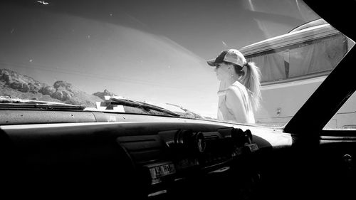 Woman standing on car against sky