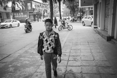 Full length of boy standing on sidewalk