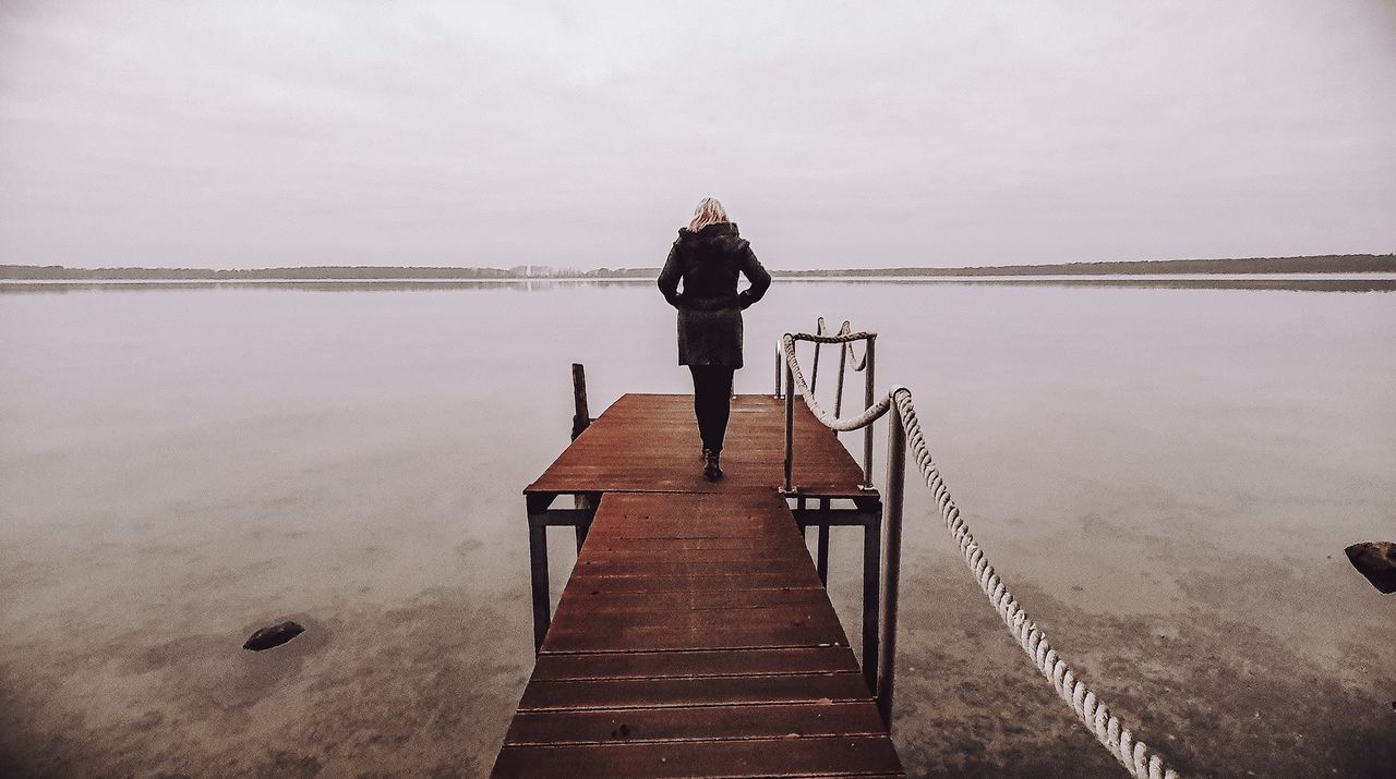 water, sky, one person, reflection, pier, nature, full length, sea, rear view, tranquility, adult, beauty in nature, jetty, scenics - nature, tranquil scene, morning, beach, lifestyles, the way forward, wood, cloud, solitude, men, standing, land, leisure activity, day, women, outdoors, vacation, architecture, trip, railing, holiday, non-urban scene, idyllic, relaxation, ocean, landscape, horizon, environment, coast, travel, horizon over water, shore