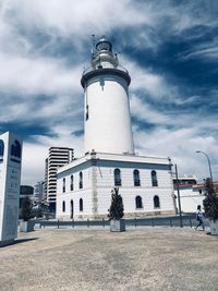 Lighthouse amidst buildings in city against sky