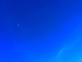 Low angle view of moon against blue sky