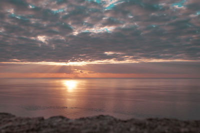 Scenic view of sea against dramatic sky during sunset