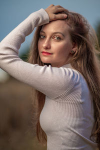 Portrait of young woman standing against sky