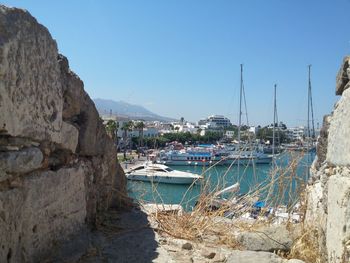 Sailboats moored at harbor against clear blue sky