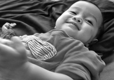 Close-up of smiling baby girl lying on bed