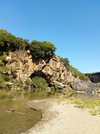 Rock formation amidst trees against clear blue sky