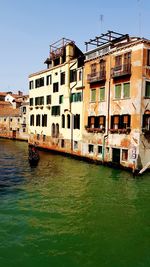 Canal by buildings against sky in city