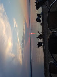 Silhouette people on beach against sky during sunset