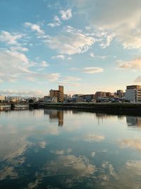 Reflection of buildings in river against sky during sunset