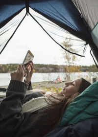 Side view of young woman using digital tablet in tent