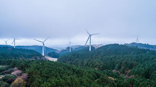 Wind turbines on landscape against sky