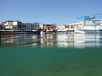 Boats moored on lake by buildings against clear sky