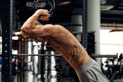 Shirtless man exercising at gym