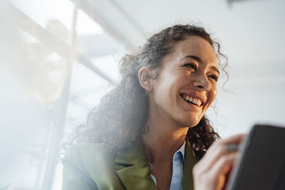 Young businesswoman with curly hair laughing at office