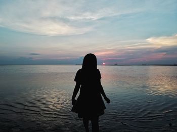 Rear view of man standing on beach during sunset