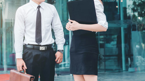 Midsection of business people standing against building