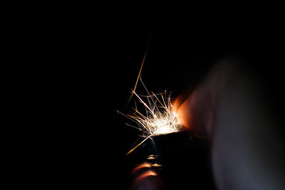 Close-up of hand holding fire against black background