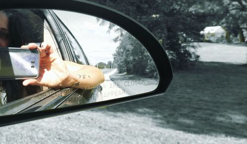 Reflection of man on side-view mirror of car