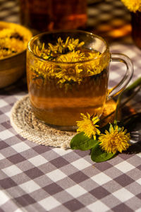 Dandelion flower healthy tea in glass teapot and glass cup on table. delicious herbal hot tea from