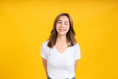 Portrait of a smiling young woman against yellow background