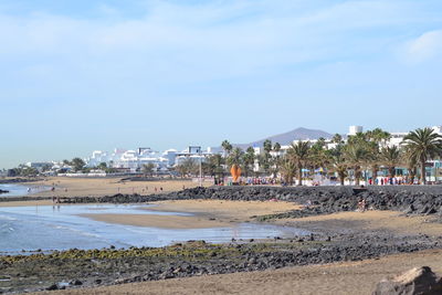 Scenic view of beach by city against sky