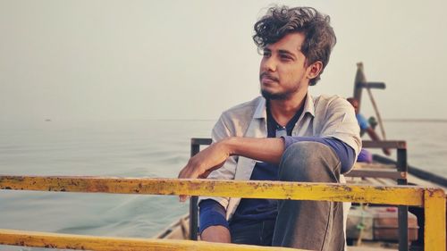 Portrait of young man standing against sea