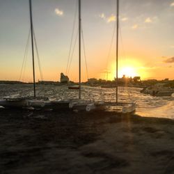 Sailboats in sea at sunset