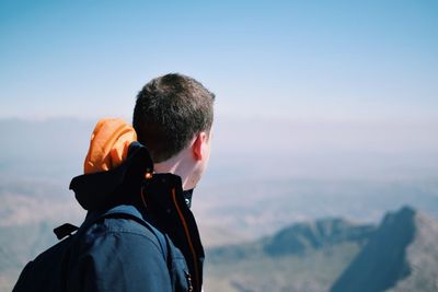 Side view of young man standing against sky