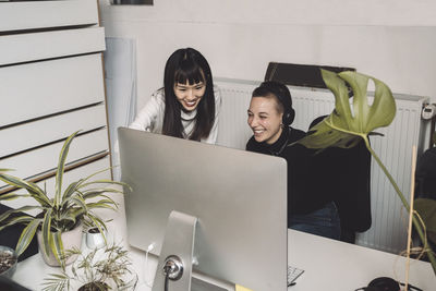 Smiling entrepreneurs working on computer at place of work