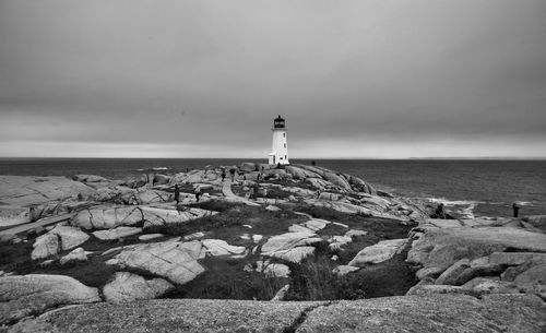 Lighthouse by sea against sky