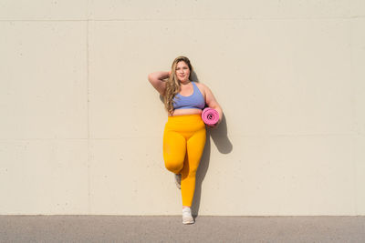 Full length of young woman standing against wall