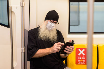 Man using mobile phone while standing on bus