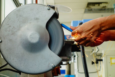 Cropped hands grinding metal in factory