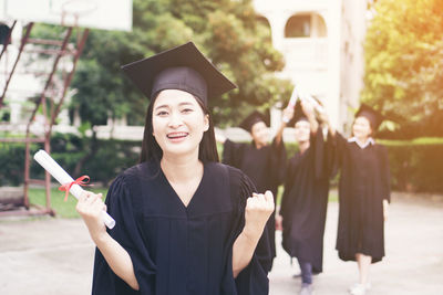 Cheerful student with clenched fist wearing graduation gown