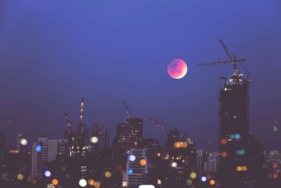 City under construction and super red blue blood moon. bokeh illuminated building.