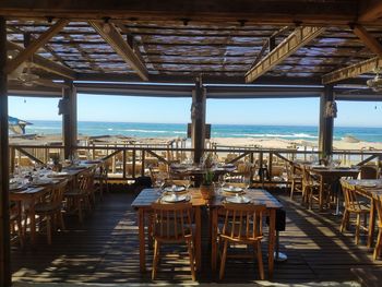 Empty chairs and tables at restaurant against sea