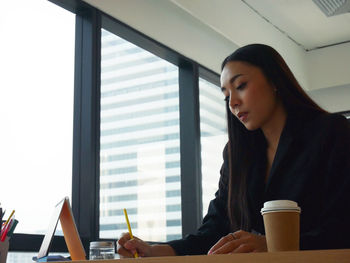 Woman looking away while sitting on table