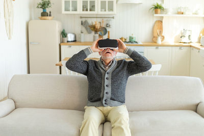 Young woman using mobile phone while sitting on sofa at home