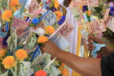 Cropped hand picking paper currency and flowers