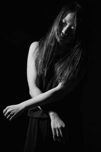 Close-up of woman standing against black background