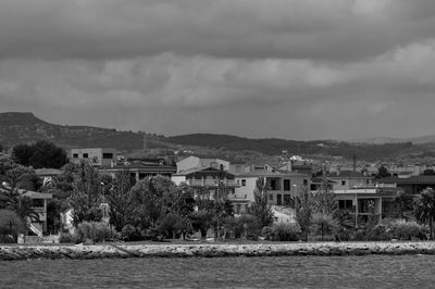 Buildings by river against sky