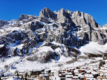 Panoramic view of rocky mountains and a village in the valley below in winter