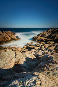 Scenic view of beach against clear blue sky