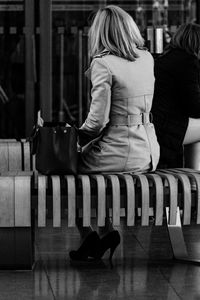 Rear view of woman sitting with purse on bench at hamburg airport