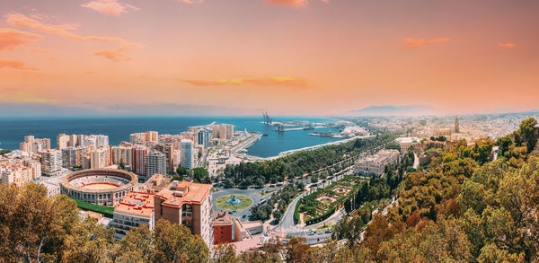 High angle view of buildings and sea against sky during sunset