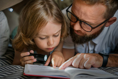 Father and son playing and reading in a kid tent at home.