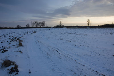 Scenic view of snow covered field against sky at sunset