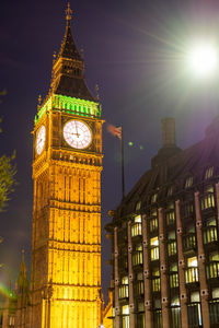 Low angle view of clock tower at night