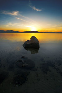 Scenic view of rocks in sea against sky during sunset