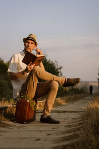 Man using mobile phone while sitting on land